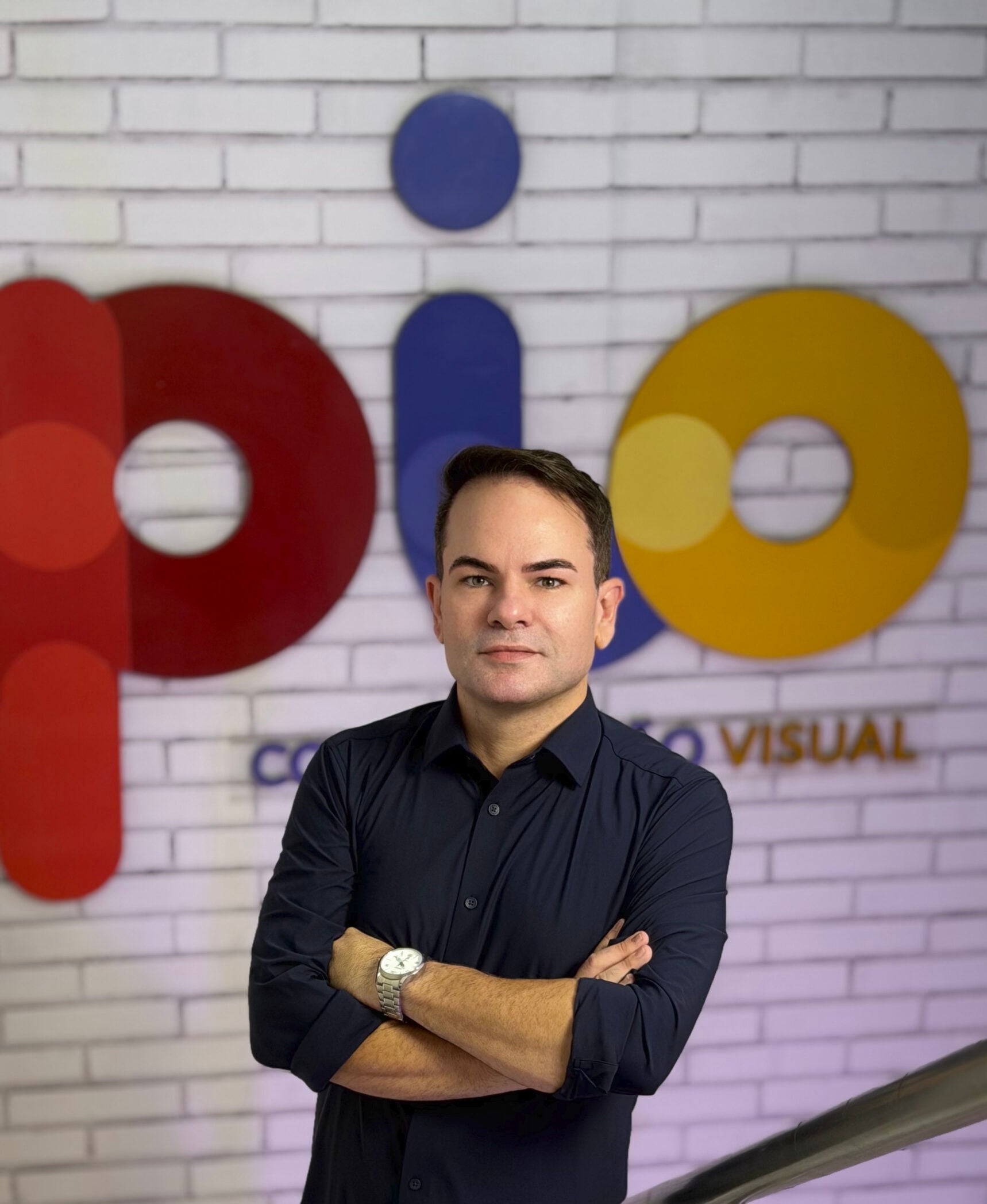 Wagner Melo diante da marca PIO Comunicação Visual